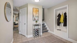 A hallway with a wine rack, a coat rack, and a staircase. - Meadowview Retreat – 3BR/3BA, Hot Tub, Ski Shuttle, East Vail (Vail)