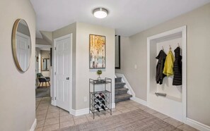 Ein Flur mit Weinkühler, Garderobe und Treppe.