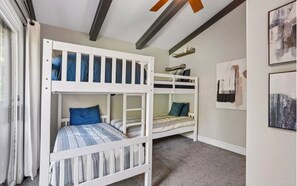 Ein Zimmer mit Etagenbetten, einem Fenster mit Vorhängen und Bildern an den Wänden.