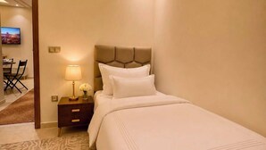 Ein Hotelzimmer mit Bett, Nachttisch, Lampe und Fernseher an der Wand.