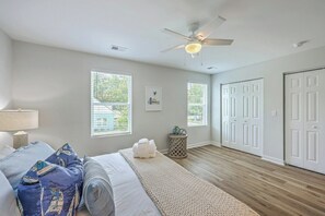 Ein Schlafzimmer mit Bett, Deckenventilator, Fenster und Tür.