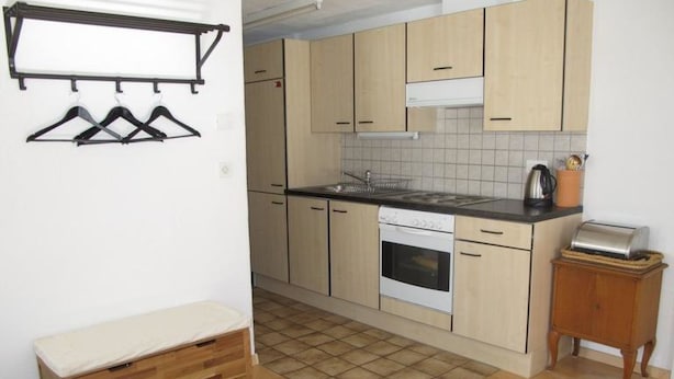 Een kleine keuken met een fornuis, oven en een klein houten kastje.
