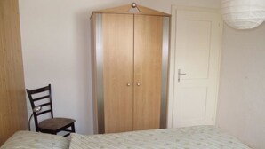 Een slaapkamer met een bed, een kledingkast, een stoel en een deur.