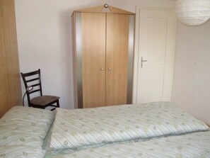 A bedroom with a bed, a wardrobe, a chair, and a door. - Helene Appartement/Fewo, Dusche, WC, 2 Schlafräume 3-Zimmerwohnung Parterre by Interhome (Adelboden)
