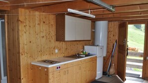 A wooden kitchen with a built-in stove, cabinets, and a sink. - Sennhütte Gibeli Hütte, Bad, WC, 4 oder mehr Schlafräume Sennhütte by Interhome (Frutigen)