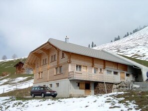 Eine Holzhütte mit geneigtem Dach, gelegen an einem mit Schnee bedeckten Hang.