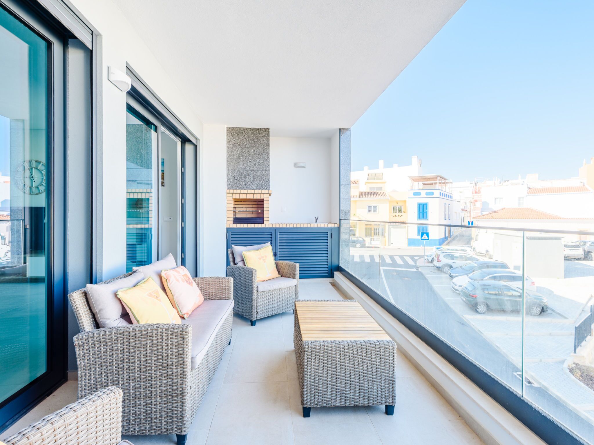 A balcony with wicker furniture, a view of the city, and a modern kitchen area.