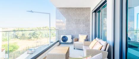 En balkon med fletmøbler, en Bosch klimaanlæg og frit udsyn til det omkringliggende område.