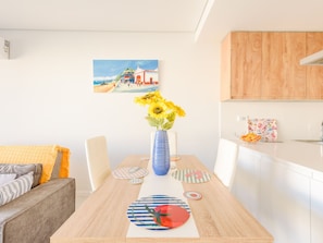 Ein Essbereich mit einem Holztisch, Stühlen, einer Vase mit Sonnenblumen und einem Bild an der Wand.