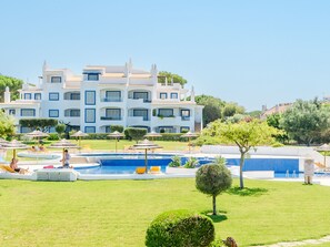 Resort com várias piscinas, espreguiçadeiras e um edifício grande com varandas.
