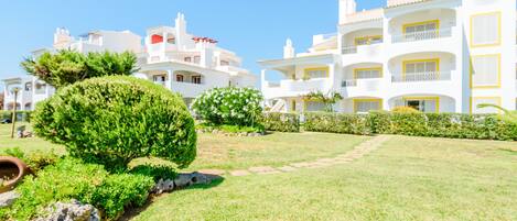 A hotel with multiple white buildings, a well-maintained lawn, and a clear sky.