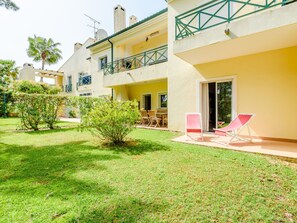 A courtyard with a small tree, a table with chairs, and a building with balconies. - Apartment  by Interhome (Vilamoura)