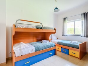 A dormitory room with bunk beds, a window with curtains, and a hanging light fixture. - Apartment  by Interhome (Vilamoura)
