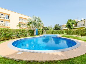 A swimming pool surrounded by a paved deck, with a building in the background. - Apartment  by Interhome (Vilamoura)