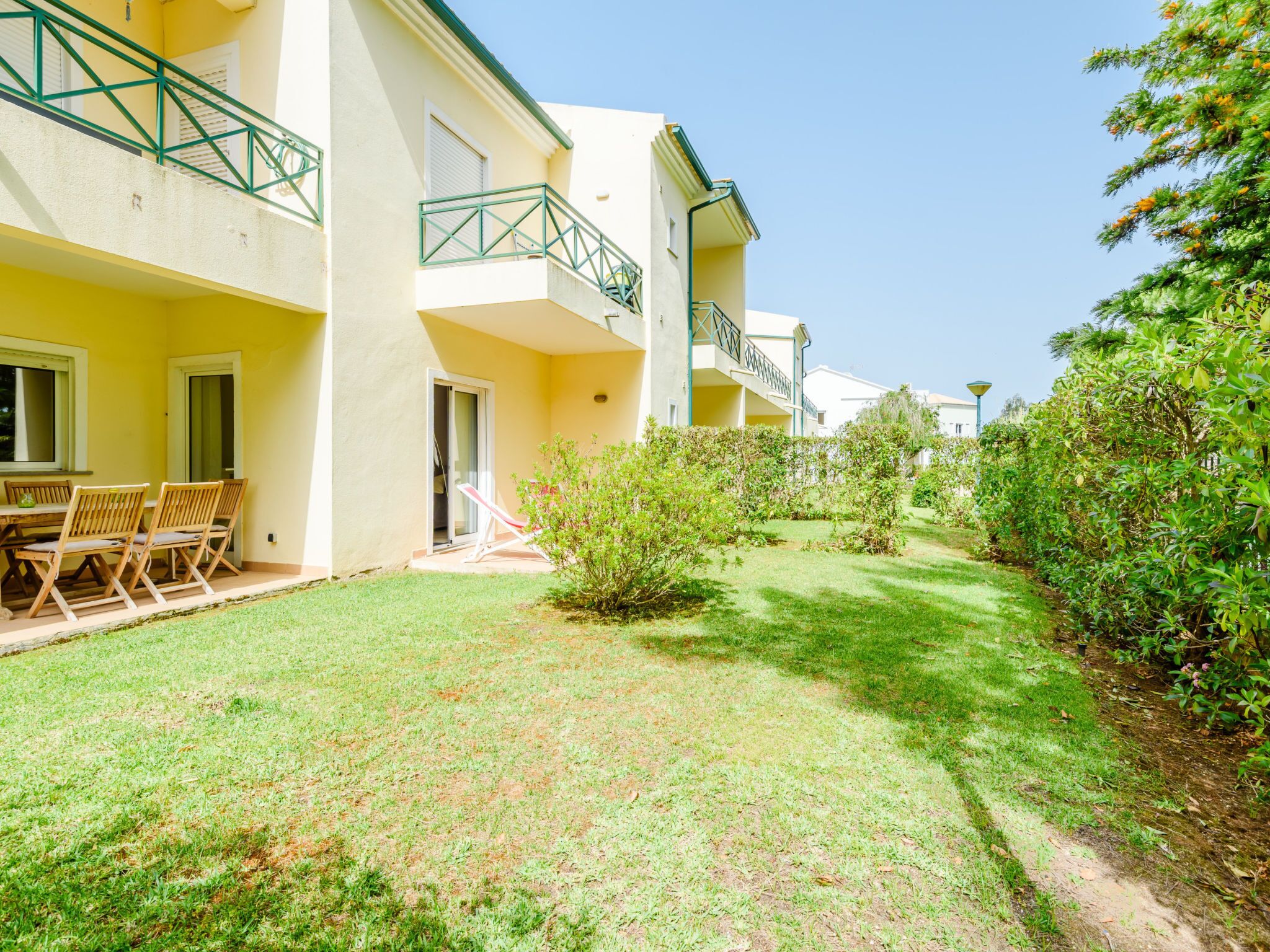 A residential building with a covered outdoor seating area and a well-maintained lawn.