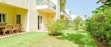 A residential building with a covered outdoor seating area and a well-maintained lawn.