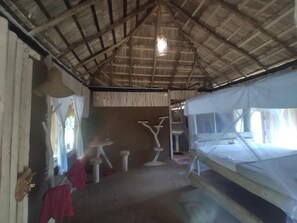A rustic room with a thatched roof, a bed, a small table, and a chair. - Nature Kingdom Sri Lanka (uva province)