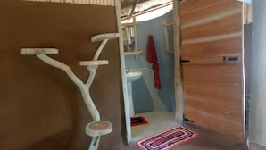 Une pièce avec une porte en bois, un vélo d’appartement blanc, un petit tabouret, une serviette rouge et un lavabo blanc.