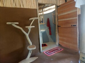 A room with a wooden door, a white exercise bike, a small stool, a red towel, and a white sink. - Nature Kingdom Sri Lanka (uva province)