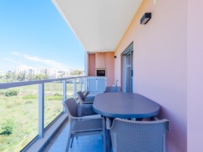 A balcony with a table and chairs, a grill, and a view of the cityscape. - Apartment  by Interhome (Praia da Rocha)