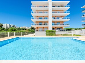 Ein mehrstöckiges Gebäude mit Balkonen, einem Schwimmbecken und blauem Himmel.