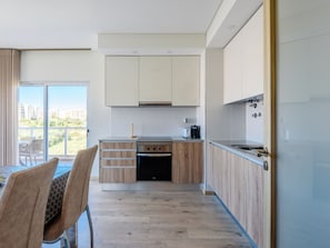 A modern kitchen with wooden cabinets, a built-in oven, and a dining area with a table and chairs. - Apartment by Interhome (Praia da Rocha)