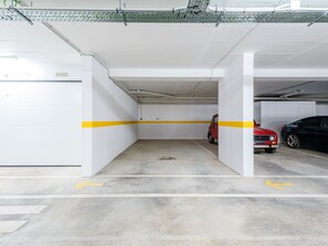 Garagem de estacionamento com piso de concreto, paredes brancas e linhas amarelas demarcando as faixas.