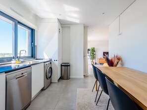 A modern kitchen with a dishwasher, washing machine, and a trash bin. - Apartment  by Interhome (Tavira)
