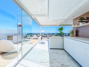 Ein modernes Interieur mit einer Glaswand, einem weißen Sofa und Blick aufs Meer.