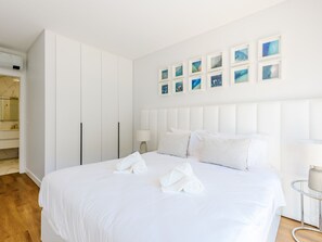 Ein Hotelzimmer mit einem großen Bett, einem Kleiderschrank, einem Spiegel und einer Wand mit gerahmten Bildern.