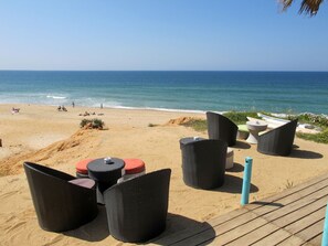 A beachside seating area with wicker furniture and a view of the ocean. - Apartment  by Interhome (Vale do Lobo)