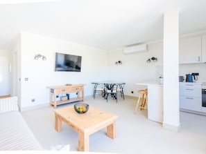 A modern apartment with a dining area, kitchen, and a TV mounted on the wall. - Apartment  by Interhome (Vale do Lobo)