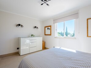 Ein Schlafzimmer mit Bett, Kommode, Spiegel und einem Fenster mit Aussicht.