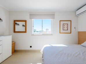 A bedroom with a bed, a window, a wardrobe, and two framed pictures on the wall. - Apartment  by Interhome (Vale do Lobo)