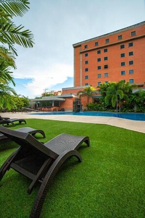 A hotel with a swimming pool, lounge chairs, and a well-maintained lawn. - Hotel GH Guaparo Inn Valencia (Naguanagua)