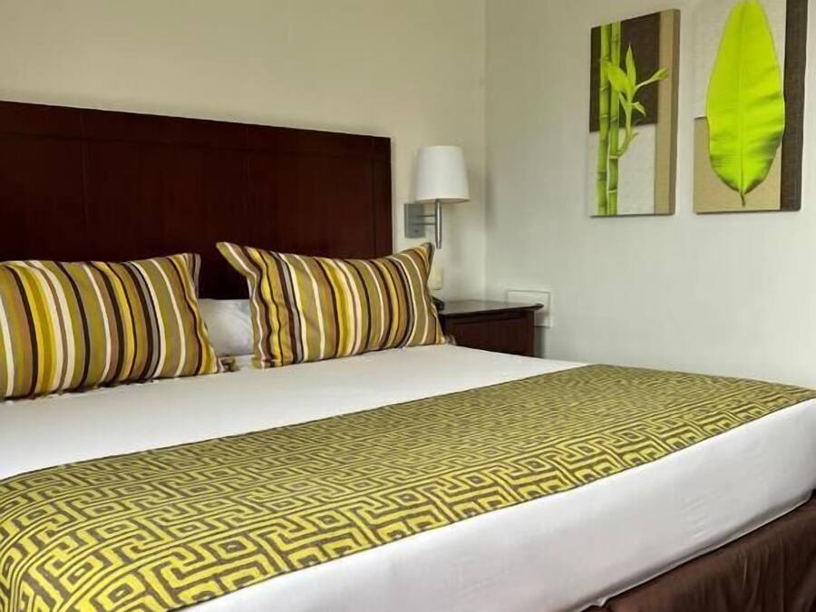 A hotel room with a bed, a nightstand, and wall art.