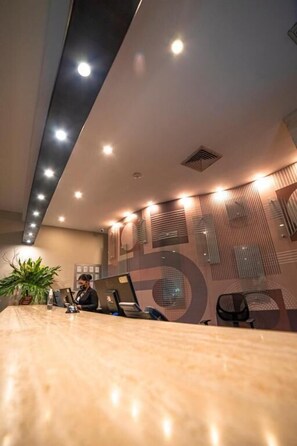 A modern office interior with a long conference table, multiple chairs, and a person working at a desk. - Hotel GH Guaparo Inn Valencia (Naguanagua)