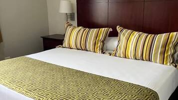 Een hotelkamer met een groot bed, een houten hoofdbord, een nachtkastje en een lamp.