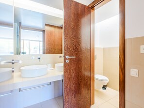 A modern bathroom with a wooden door, a round sink, and a toilet. - Apartment  by Interhome (Guia)
