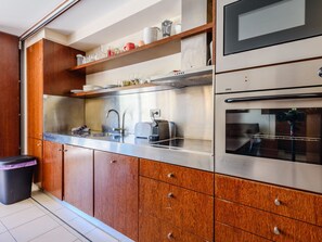Une cuisine moderne dotée d’appareils électroménagers en acier inoxydable, de meubles en bois et d’un four encastré.