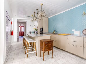 Eine moderne Küche mit einer zentralen Kochinsel, Barhocker, einem Holztisch und einer blauen, gefliesten Rückwand.