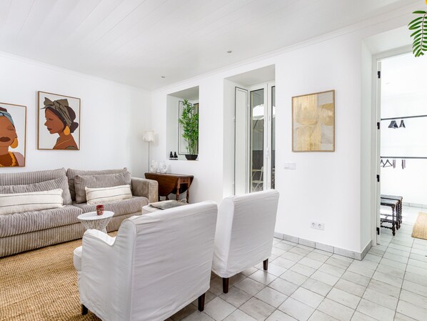 Ein modernes Wohnzimmer mit einer Couch, Sesseln, einem Couchtisch und Kunstwerken an den Wänden.