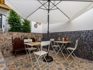 Eine Terrasse mit Tisch und Stühlen, einem großen Sonnenschirm und einer Zierwand.