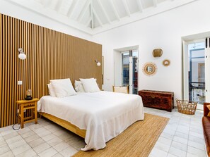 A modern bedroom with a large bed, wooden panel wall, and a view to the outside. - Apartment  by Interhome (Tavira)