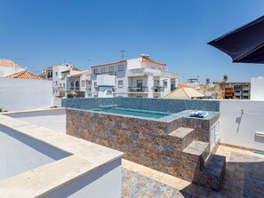 A rooftop swimming pool with a tiled border and a view of surrounding buildings. - TaviraBliss Terrace Apartment by Interhome (Tavira)
