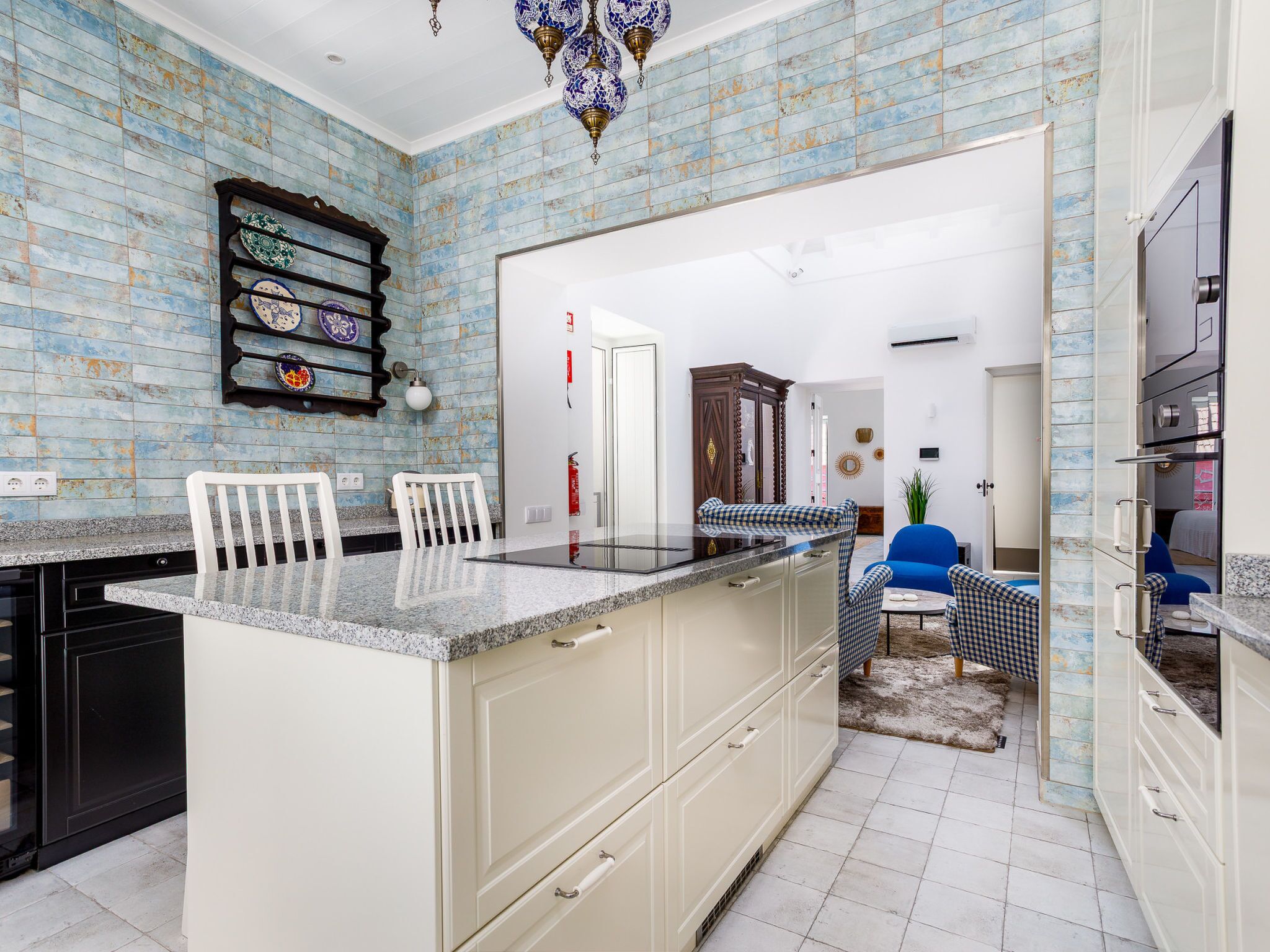 A kitchen with a central island, white cabinetry, and a blue and white tiled backsplash.