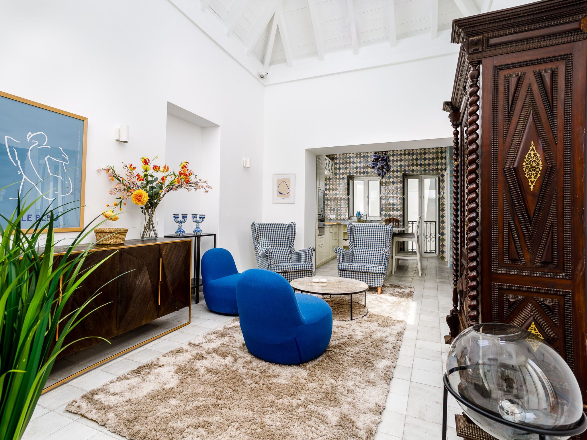 A modern living room with a sofa, armchairs, a coffee table, and a decorative cabinet.