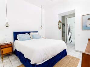 Une chambre à coucher avec un grand lit, des tables de chevet, un miroir et une porte donnant sur une salle de bain.