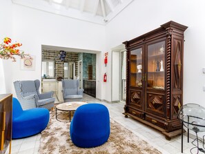 A living room with blue armchairs, a coffee table, a wooden cabinet, and a kitchen in the background. - TaviraBliss Terrace Apartment by Interhome (Tavira)