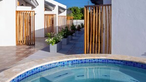 A swimming pool with a tiled edge, surrounded by white walls and wooden fences. - Aruba Vibe Apartments #2 | A charming place near the beaches and the city center (Oranjestad)
